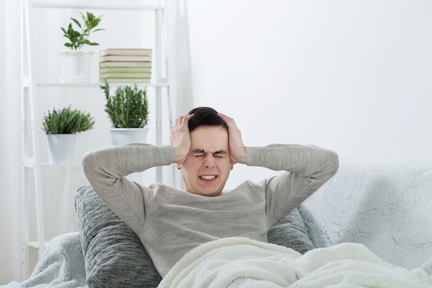 A man with a headache on the sofa