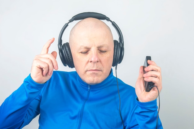 Foto uomo con cuffie e lettore portatile digitale nelle mani in relax mentre si ascolta la sua musica preferita