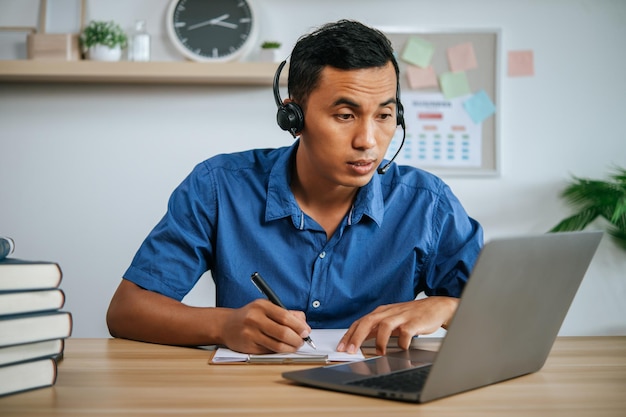 Uomo con le cuffie che lavora in ufficio con documenti e laptop sulla scrivania