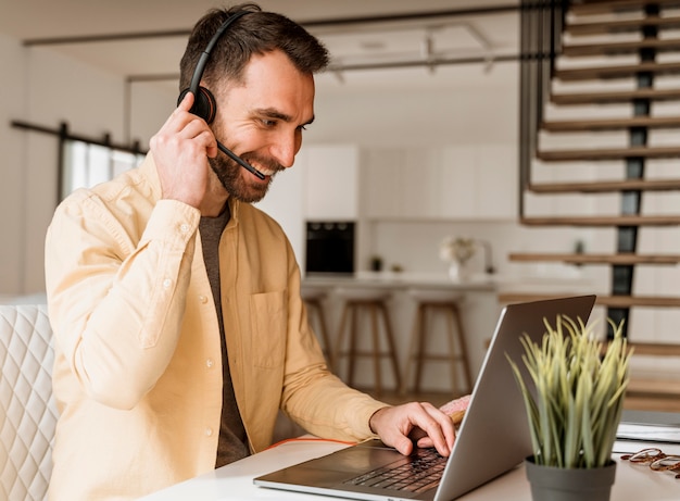 Uomo con auricolare che ha videochiamata sul computer portatile