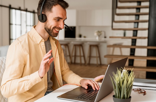 Photo man with headset having video call on laptop