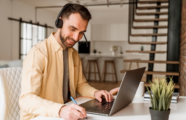 Photo man with headset having video call on laptop