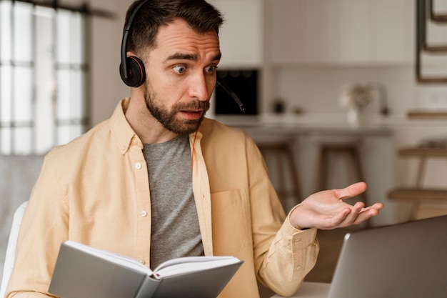 Foto uomo con auricolare che ha videochiamata sul computer portatile