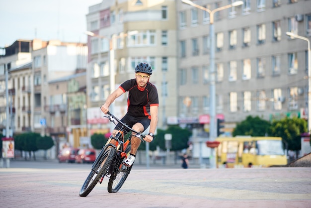 自転車に乗ってヘルメットを持つ男