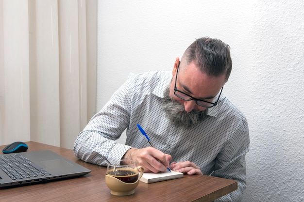 Man with hipster beard writing notes at home