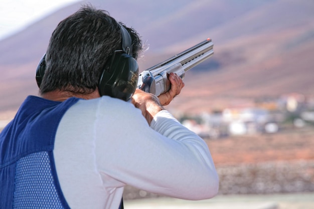 man with his back practicing clay pigeon shooting