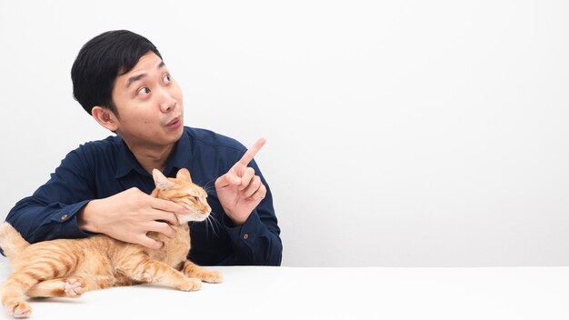 Man with his cat orange color point finger at copy space on the table