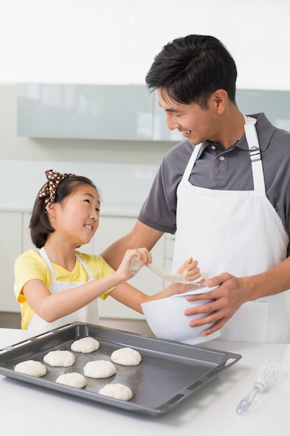 Man with his daughter preparing cookies in kitchen