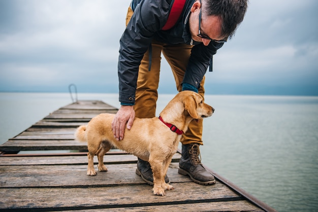 ドックに立っている彼の犬を持つ男