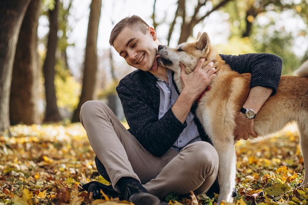 秋の公園を歩いている彼の犬を持つ男