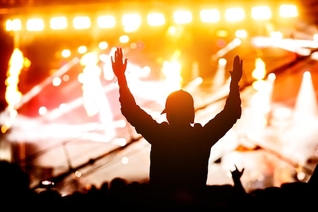 A man with his hands up at a concert of his favorite group