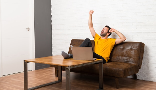 Man with his laptop in a room celebrating a victory in winner position