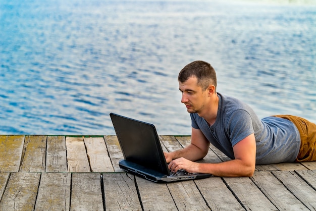 A man with his notebook is working outdoor at the lake