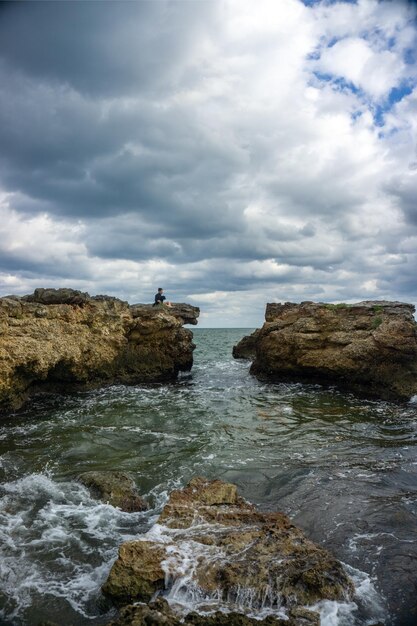 man with his puppy sitting in a bay watching the sea