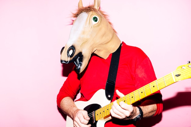 エレクトリックギターを弾く馬のマスクを持つ男