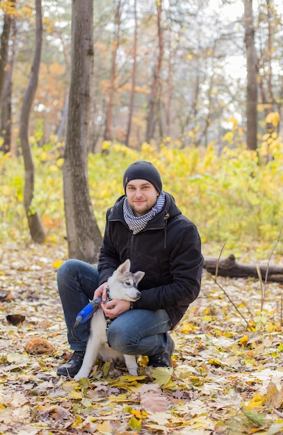 Man with husky puppy in autumn in the park