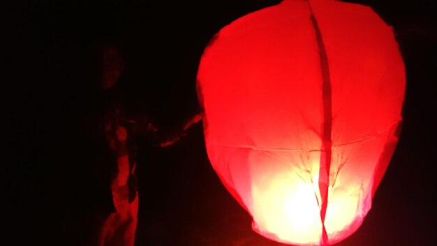 Man with illuminated paper lantern at night