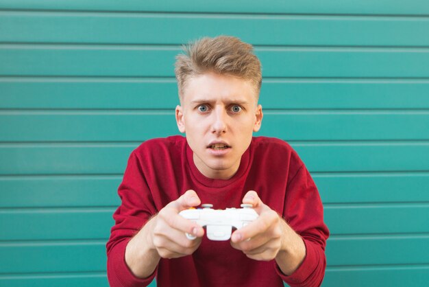 Man with a joystick in his hands plays video games on turquoise