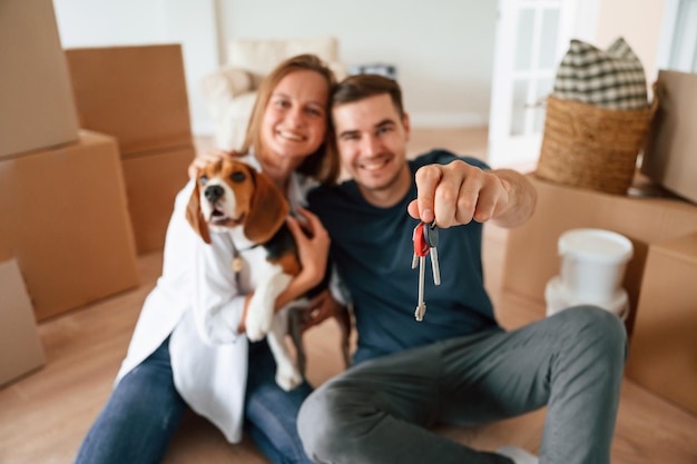 Foto l'uomo con le chiavi una giovane coppia con il cane si sta trasferendo in una nuova casa