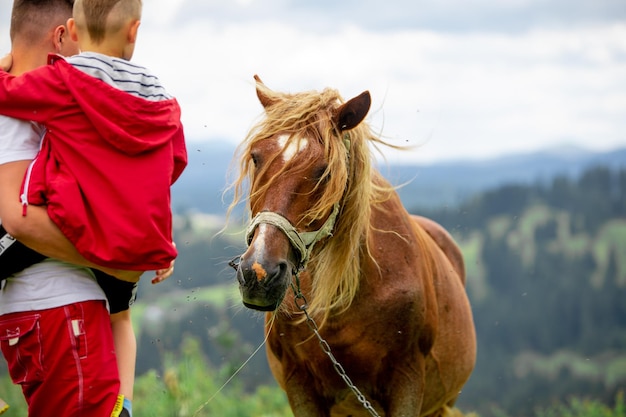 子供を持つ男は、背景に馬の山をかわいがります