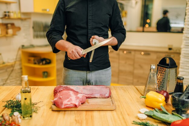 Man with knife prepares to cut raw meat