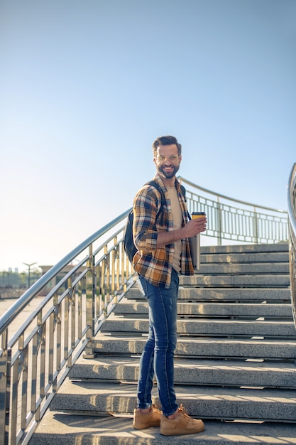 Man with laptop and coffee going downstairs