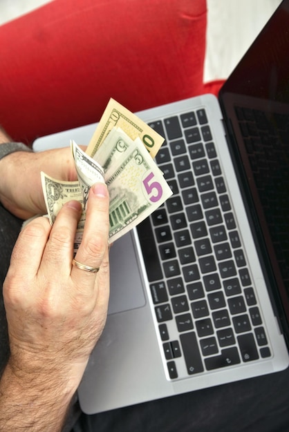 Man with laptop on lap and money in hands closeup online
business concept