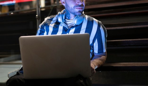 Man with laptop in night city, unrecognizable face