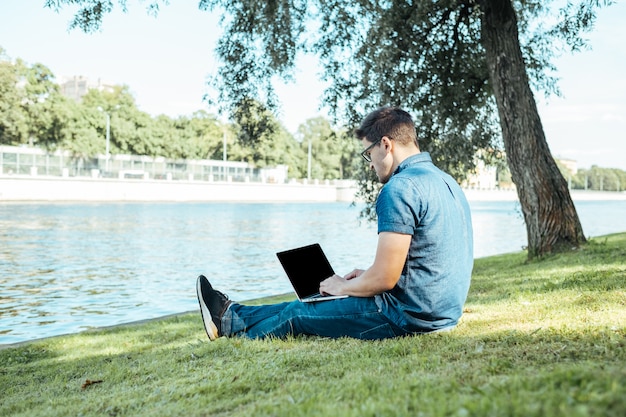 Man with laptop sitting outdoors in nature