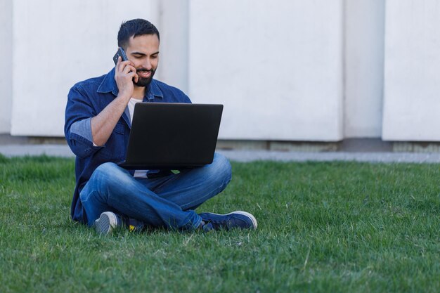 Man with laptop and smartphone at summer park on bright day