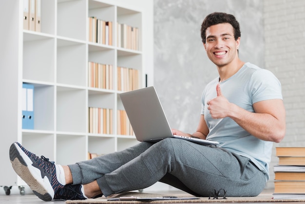 Uomo con il portatile circondato da libri