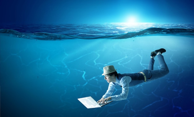 Man with laptop underwater. Mixed media