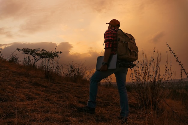 Man with a laptop walking at sunset