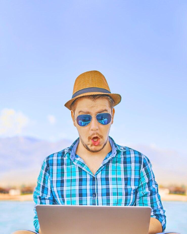 Man with laptop working remotely on colorful beach of island