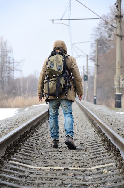 Un uomo con un grande zaino va avanti sui binari della ferrovia