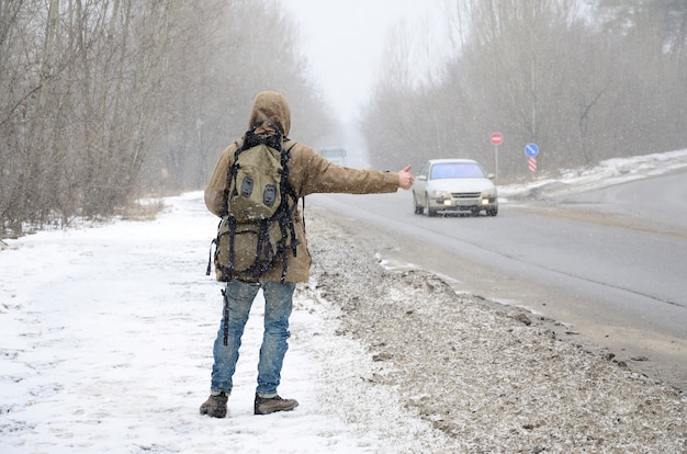 Photo a man with a large backpack showing thumbs up for hitchhiking du
