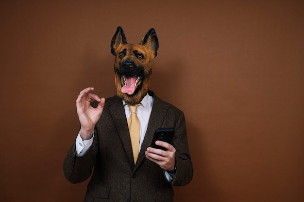 Мужчина в латексной маске на голове собаки и смартфоне