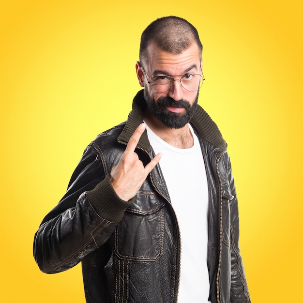 Man with leather jacket making horn gesture on colorful background