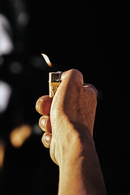 Man with lighter in his hands on dark background