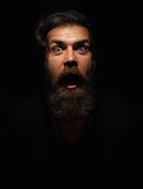 Foto uomo con barba lunga ritratto di profilo hipster silhouette di uomo serio occhi aperti guardando in avanti ritratto di giovane uomo su uno sfondo scuro.