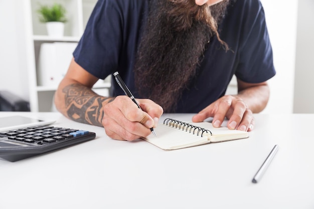 Man with long beard is taking notes