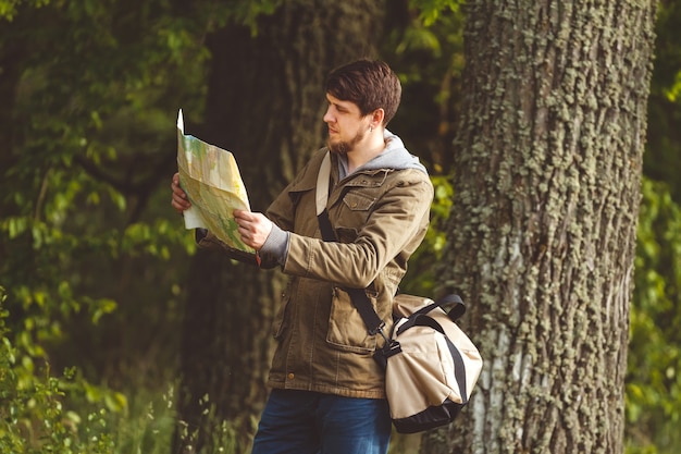 Uomo con mappa e borsa in mano camminando su una strada