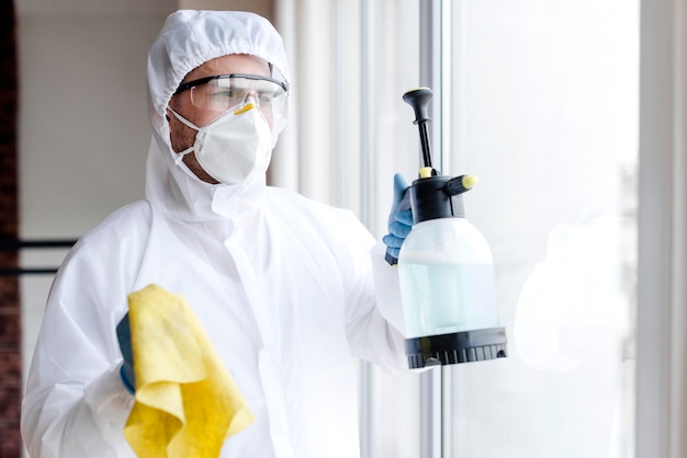 Man with mask disinfecting window