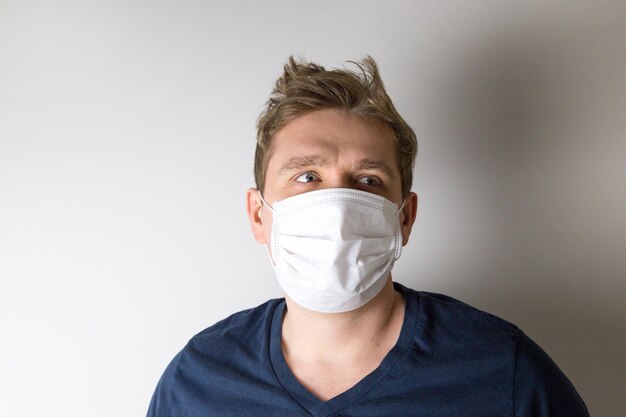 Man with mask to protect him from virus. The concept of the epidemic of the coronavirus. Tired Doctor with medical white mask.