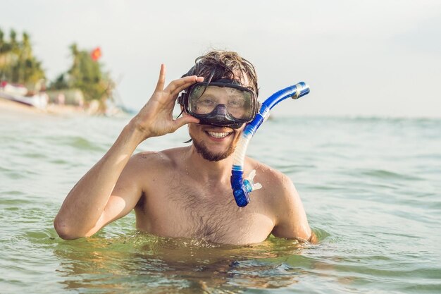 A man with a mask and snorkel is going to dive into the sea.