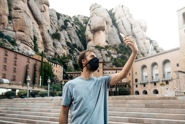 Man with mask taking a selfie photo in the montserrat monastery, Barcelona, Spain