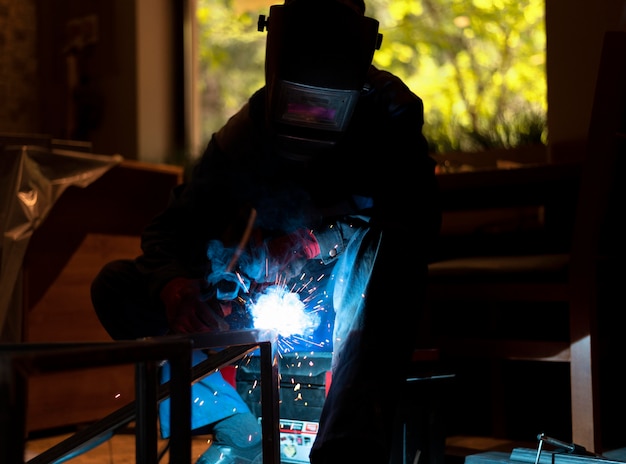 Foto uomo con maschera che salda metallo nell'atelier