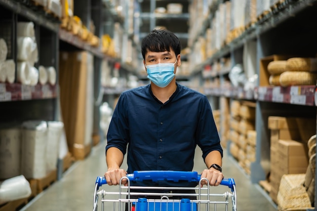 Мужчина в медицинской маске смотрит и делает покупки в складском магазине во время пандемии коронавируса