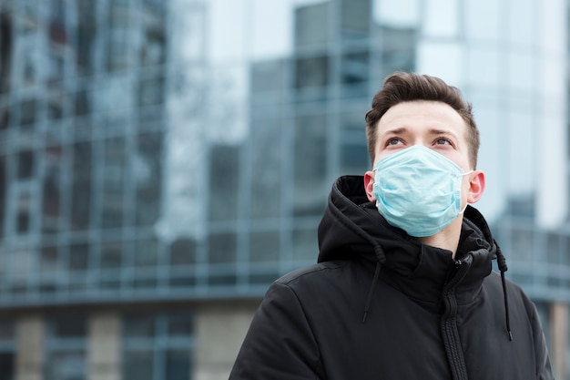 Uomo con la mascherina medica che propone nella città con lo spazio della copia