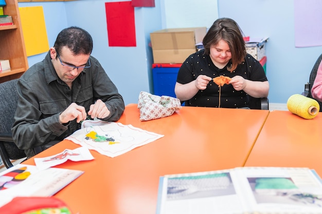 A man with mental disabilities and Down Syndrome focuses on sewing